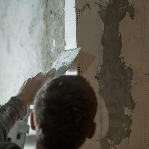 a male plasterer plasters a wall with a spatula.