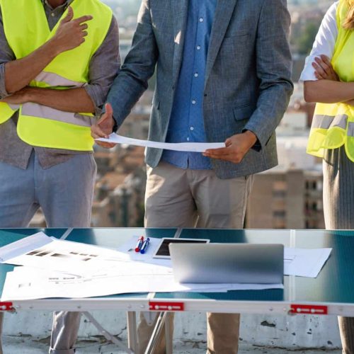 Diverse team of specialists with computer on construction site. Building project with engineers